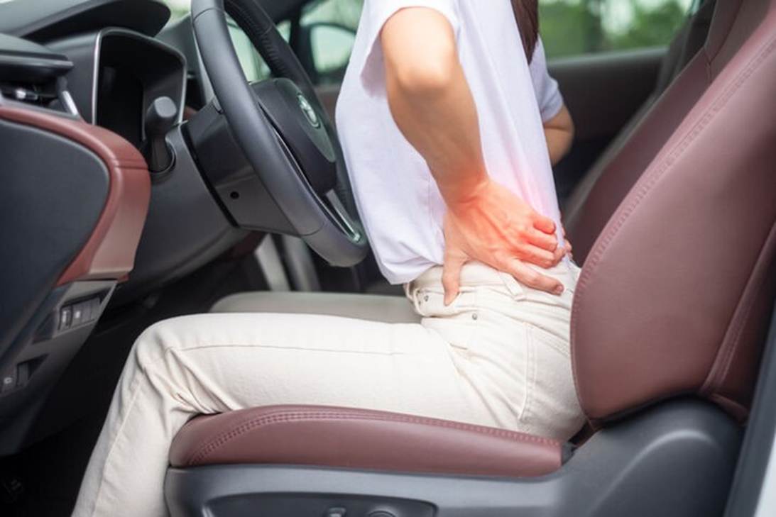 A person holding her back while sitting in a car

AI-generated content may be incorrect.